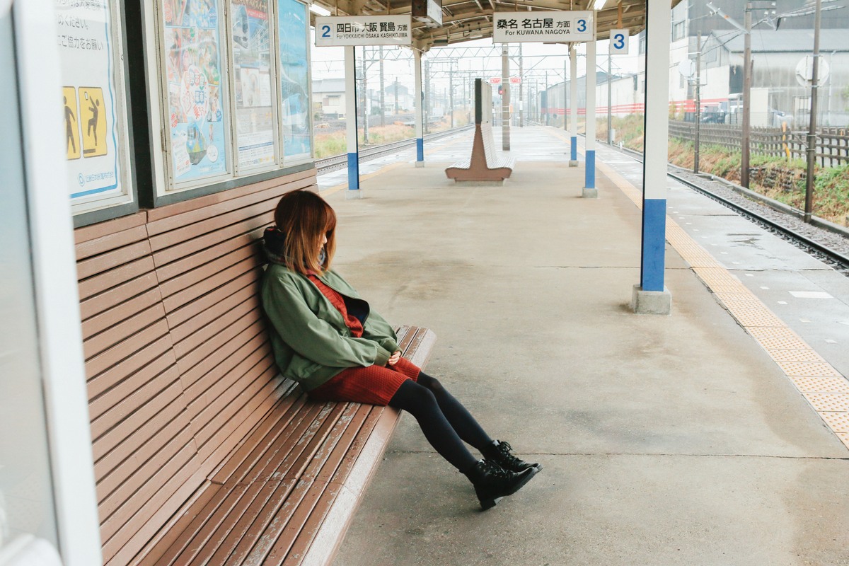 駅のホームのベンチに一人で座る彼女。